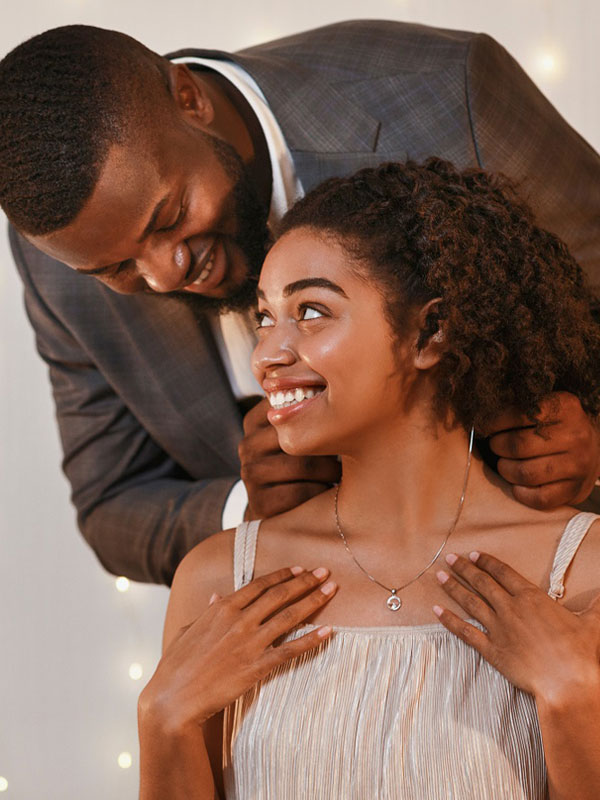 young couple with man putting necklace on girlfriend