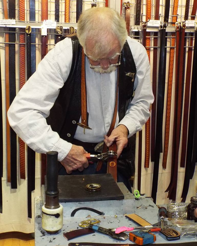 man wearing glasses handcrafting jewelry at fair