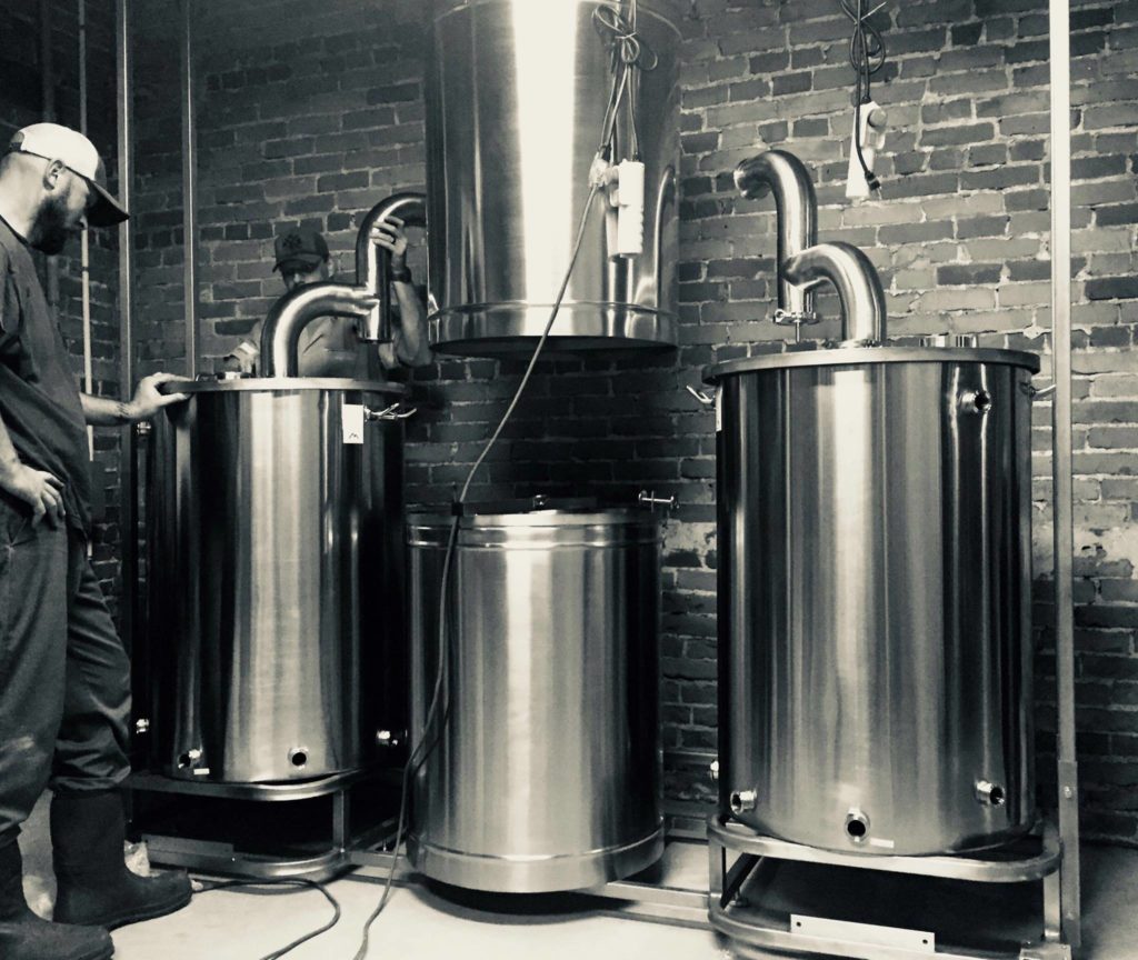 man standing by beer making equipment